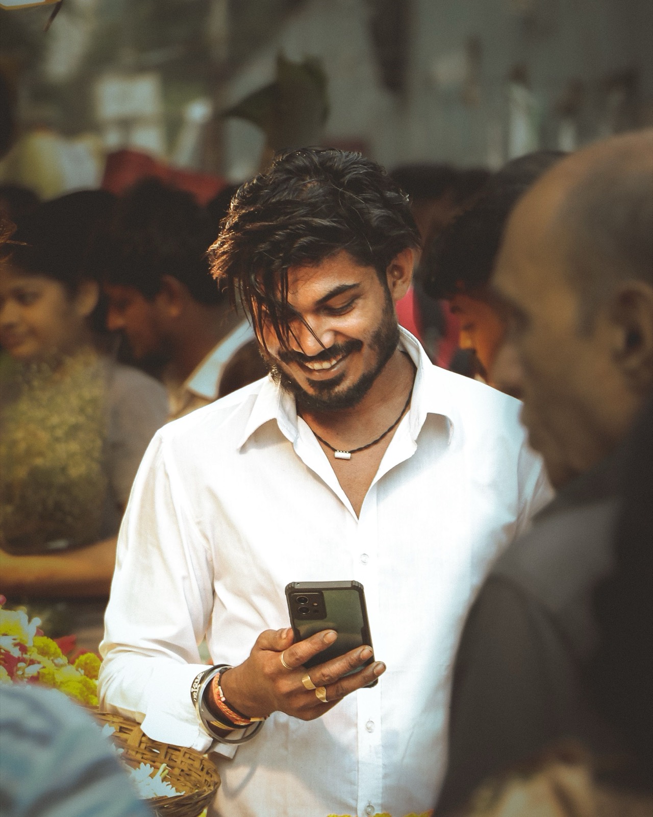 Sales rep smiling while glancing at his phone in a busy outdoor setting